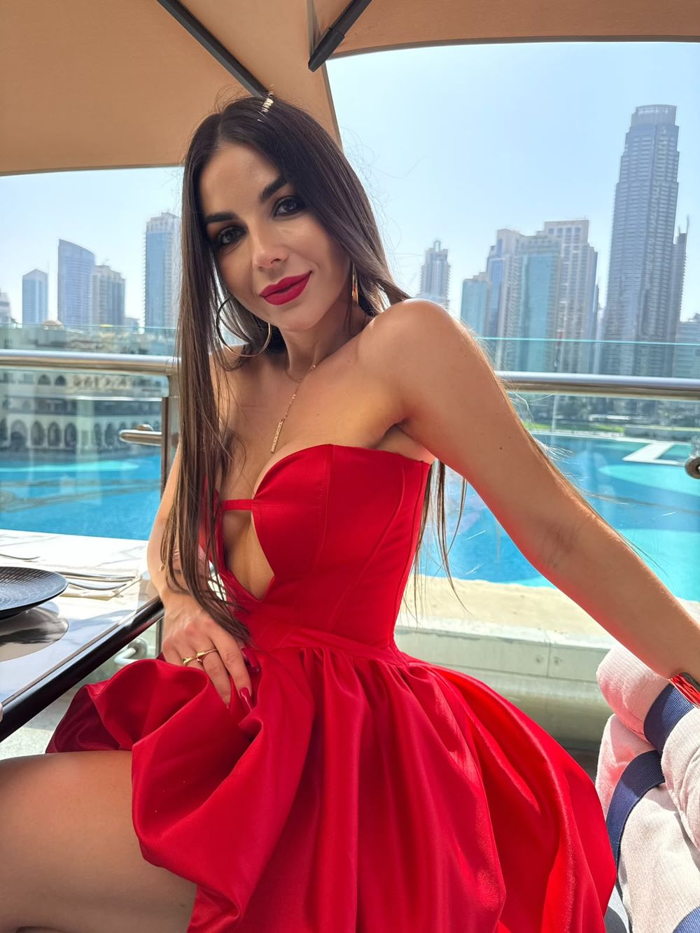 Liliia in a red dress on a terrace above the Dubai skyline