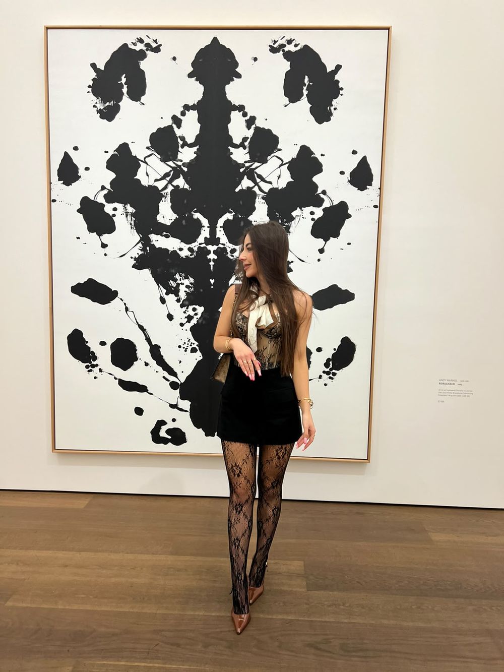 Liliia in a gallery in front of a large ink-blot painting
